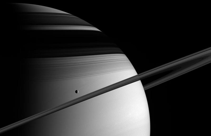 Tethys, Satürn ün halkaları ve halkaların gezegen üzerinde oluşturduğu gölge. Kaynak: NASA Tethys üzerindeki çukurlar şaşırtıcı bir biçimde gezegenin düzlüğü ile muhteşem bir uyum içerisindedir.